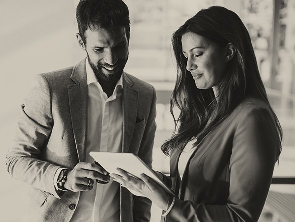 Um homem e uma mulher em pé verificando informações em um tablet
