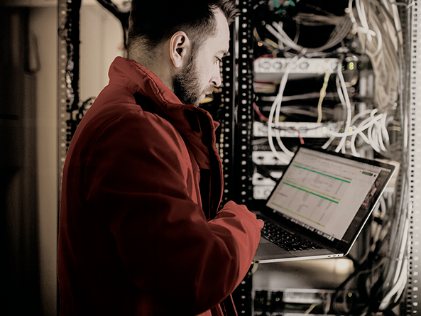 Homem com casaco vermelho com computador fazendo manutenção em um servidor
