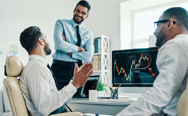 Três homens conversam em um ambiente corporativo.