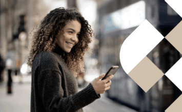 Jovem mulher mexendo no celular com cidade como fundo